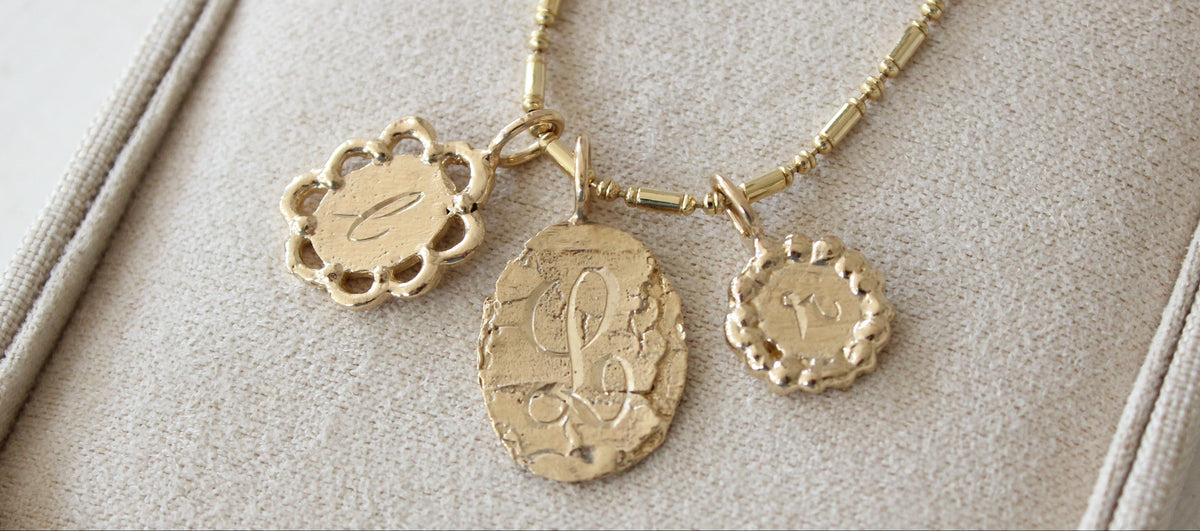 Stack of gold pendants hand-engraved with initials
