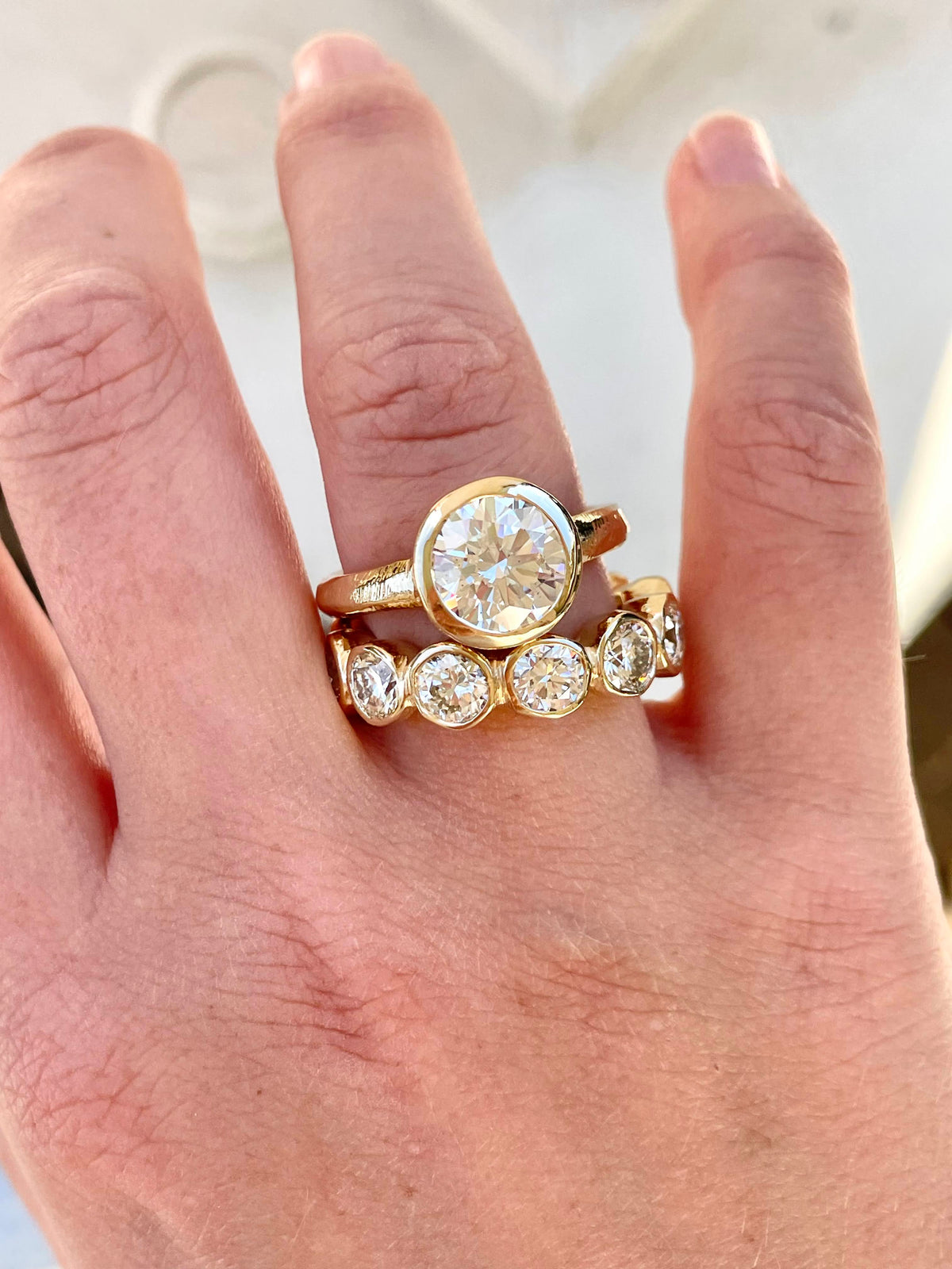 Custom engagement ring with hand-carved gold band and bezel-set diamonds by Mary Frances Maker.